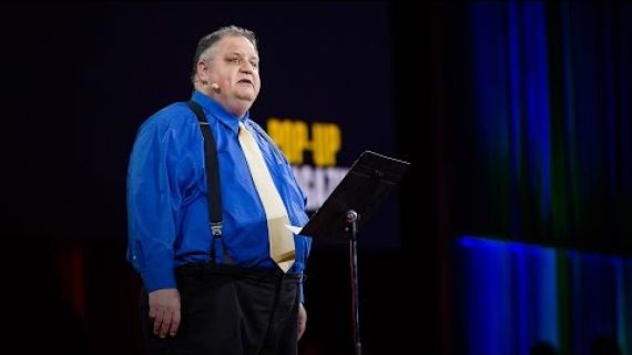 Man standing on stage with microphone speaking