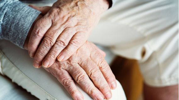 detail of older person holding hands in lap