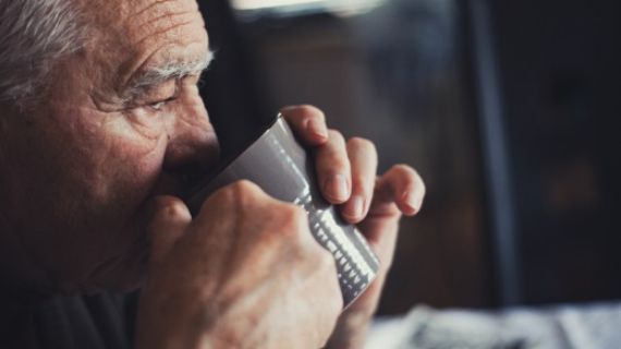 An elderly man drinking coffee