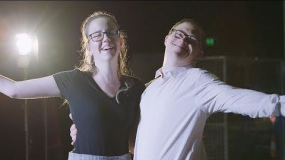 Lady and a man standing arm in arm smiling at the camera