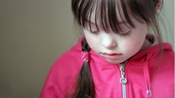 Image of young girl with Down Syndrome looking sad