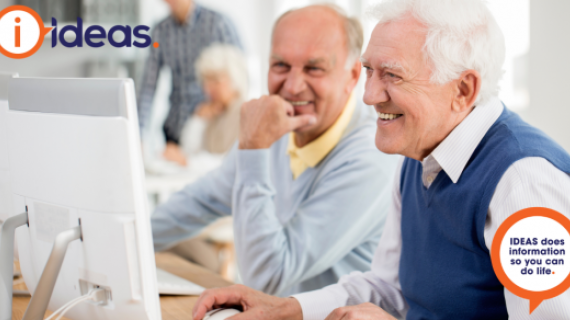 Two senior males are looking at a computer.