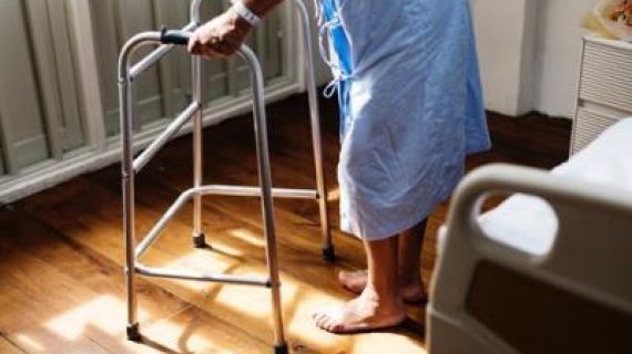 person in hospital gown using a walking frame