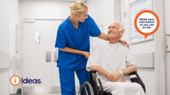 An elderly person in a wheelchair being pushed by a nurse in a hospital.