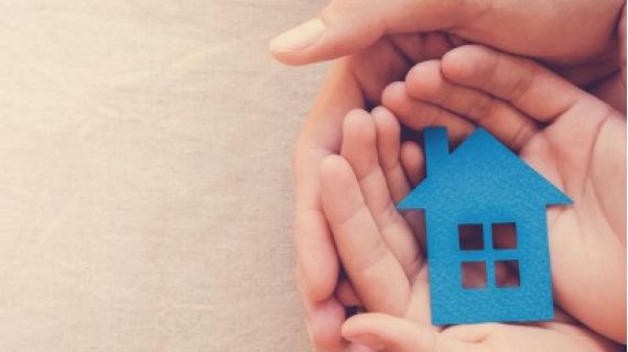 hands holding a blue house made of paper
