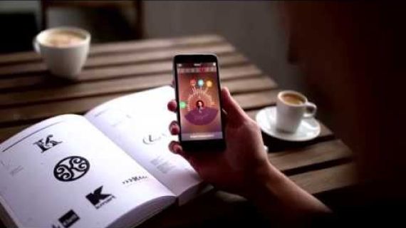 Persons hand holding mobile phone on a table with cups of coffee