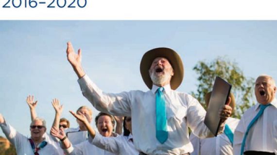 Men and women dressed in white tops singing with arms in the air