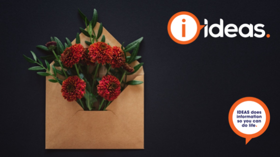 A black background with kraft envelop and redish orange flowers peeking from the envelope. Symbolising "Hope in the mail".
