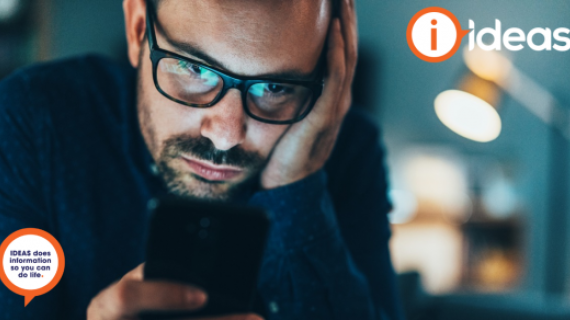 Man with glasses, resting hand on forehead, looking at his phone.