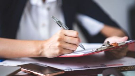 Close up photo of females hand holding a pen and filling out a form.