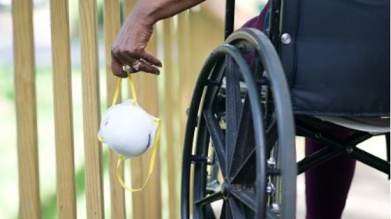 wheelchair user holding a surgical mask