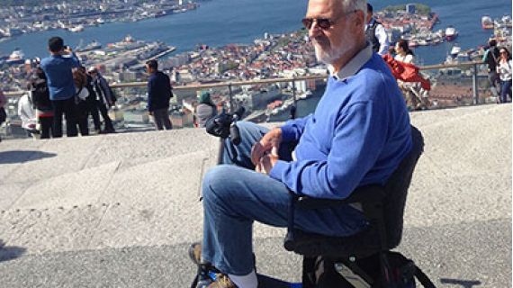 Man sitting in mobility scooter overlooking a beautiful ocean vista