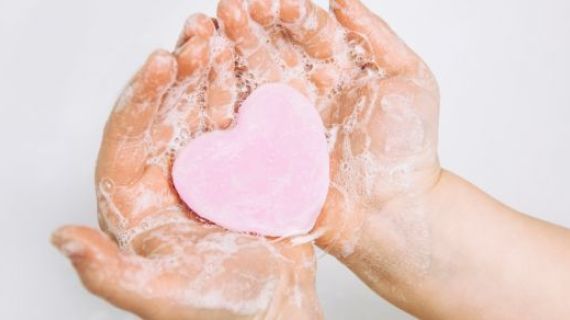 A childs hands holding heart shaped soap.