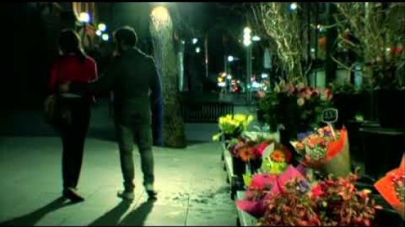 2 people walking down the street past a flower shop