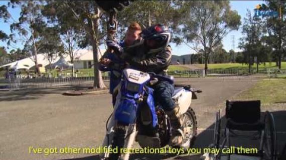 Man getting onto a motor bike from his wheelchair