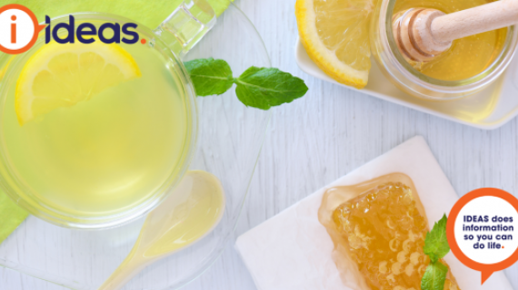 An image of a glass mug with lemon drink. Lemon, honey and comb, and a honey drizzler.
