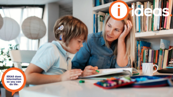 Child with cochlear implant sitting alongside an adult, learning