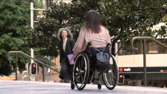 Lady in a wheelchair wheeling down the street