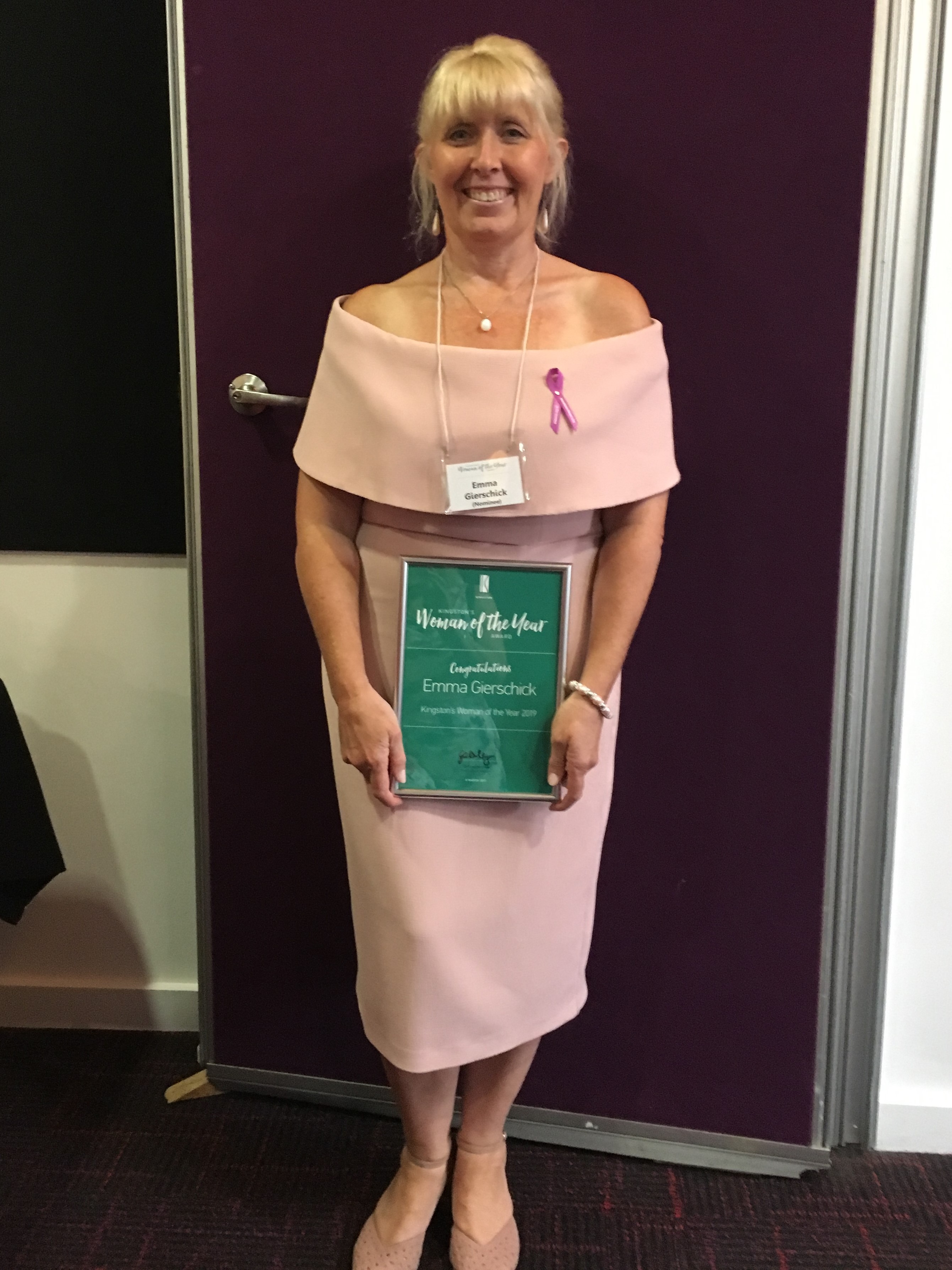 A well dressed woman is holding an award plaque.