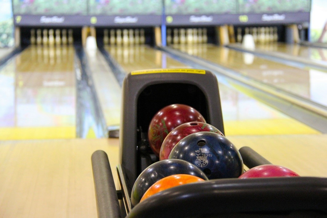 A ten pin bowling lane with the pin standing at the end and the balls held in the ball holder